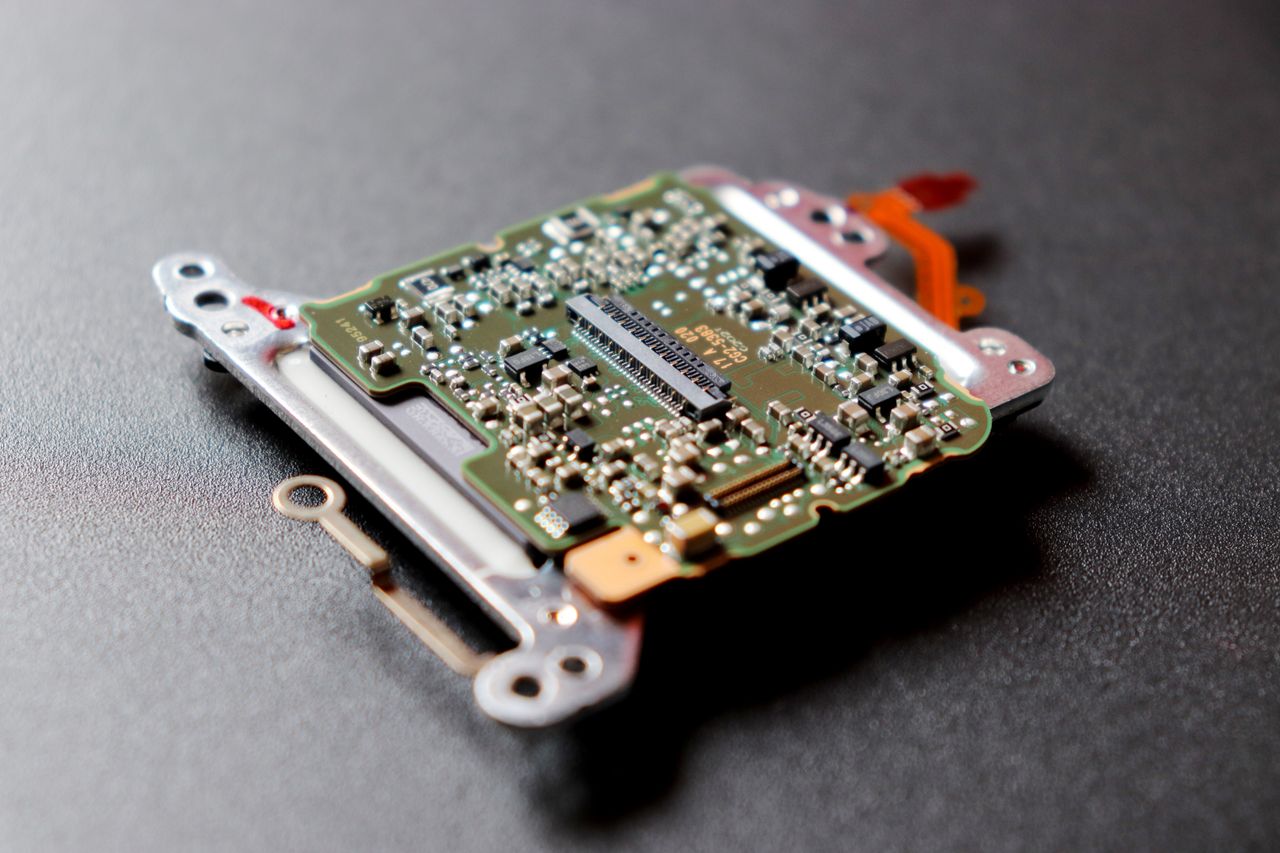 our-story Detailed view of a microchip, showcasing intricate electronic components on a dark textured surface.
